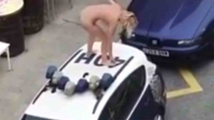 Una mujer desnuda se sube al techo de un coche de policía durante el confinamiento